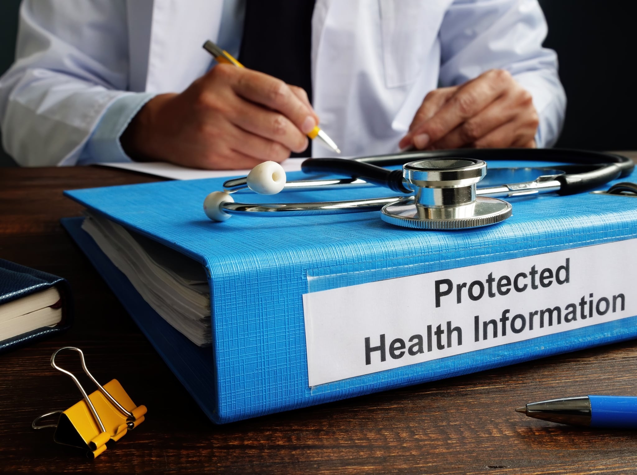 Close up of a man with a stethoscope and binder for HIPAA